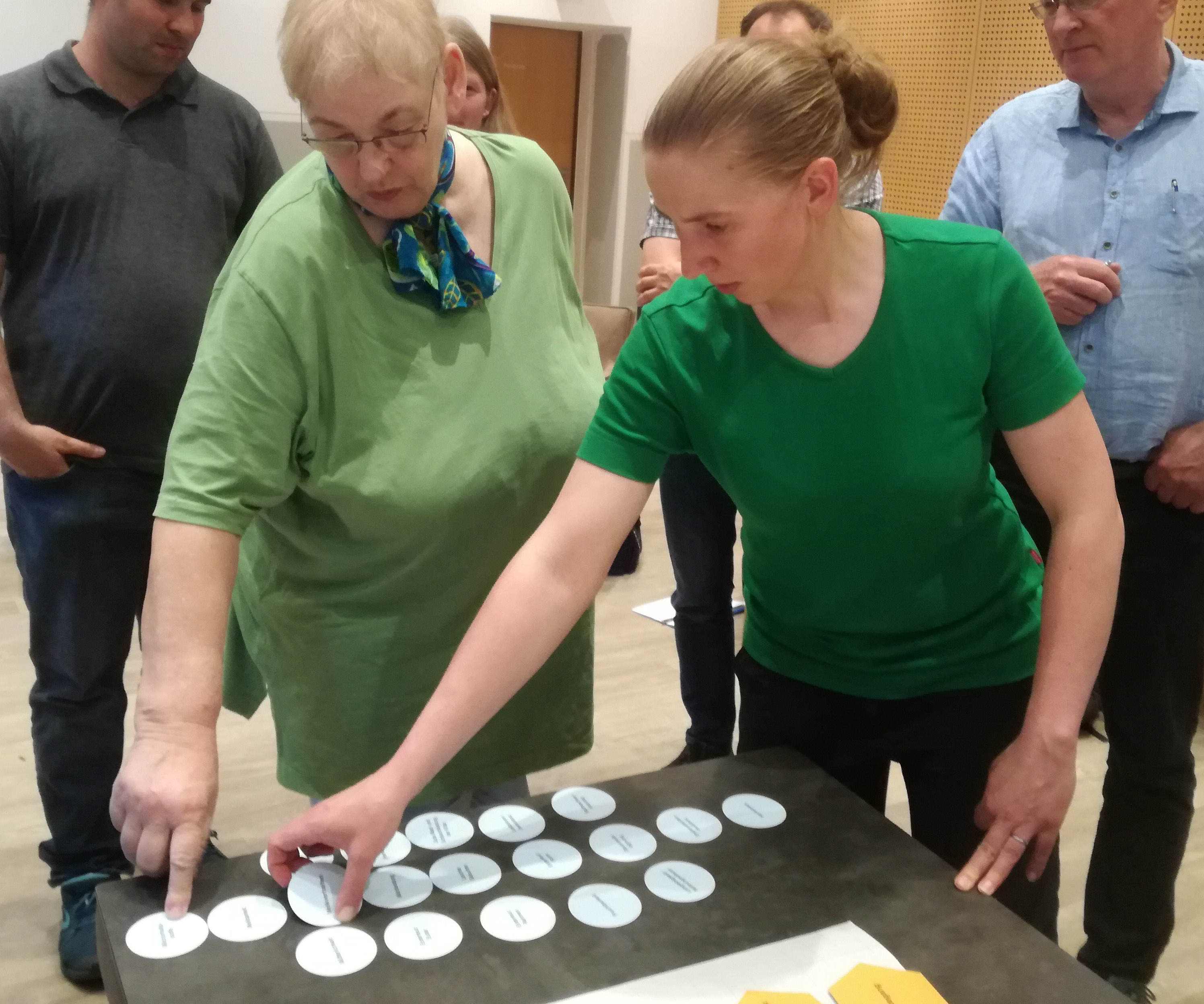 Kreiskarten werden angeordnet Zwei Damen in grünen Shirts legen ein Schema mit Kreiskarten.